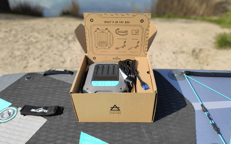 Bluefin E-Swift electric pump in its opened box on a paddleboard deck