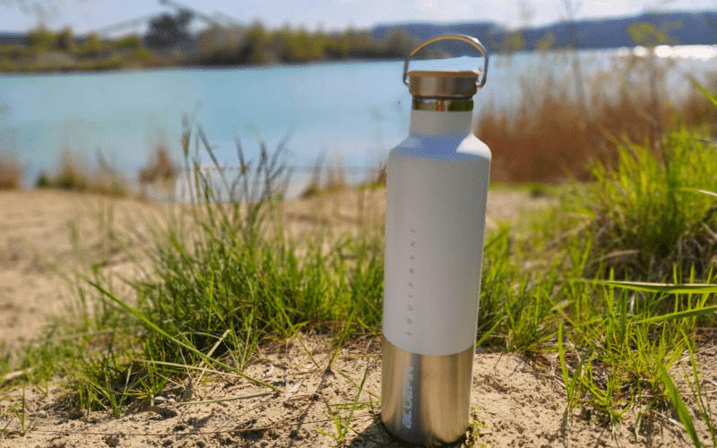 Bluefin Hi-Drate insulated bottle standing on the shore of a lake